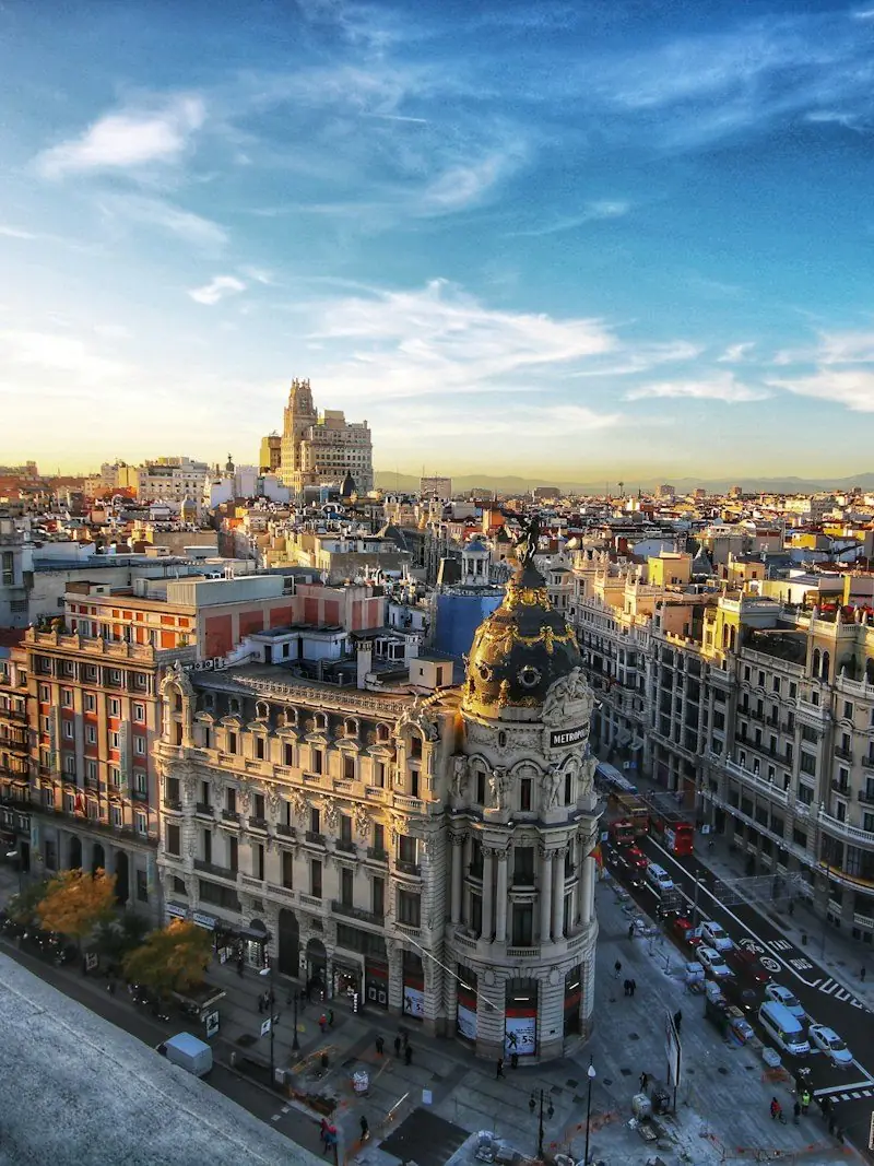 Gran Via in Madrid seen from a rooftop at golden hour, with the ornate dome of the Metropolis building catching the last light